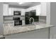 Modern kitchen with white cabinets, granite countertops, and black appliances at 1015 Stucki Ter, Winter Garden, FL 34787