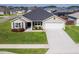 Tan house with gray roof, two-car garage, and well-manicured lawn at 11272 Stewart Loop, Oxford, FL 34484