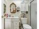 Bathroom features a white vanity, decorative mirror, and a toilet with white shelving above it at 118 Shomate Dr, Longwood, FL 32750