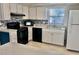 Modern kitchen featuring white cabinets, black appliances, and a tile backsplash at 13635 Berkshire Ct, Grand Island, FL 32735