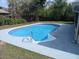 Refreshing in-ground pool with light blue liner and handrails surrounded by a concrete deck and green landscaping at 13635 Berkshire Ct, Grand Island, FL 32735