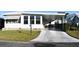 Front view of a white manufactured home with a carport and landscaping at 1401 W Highway 50 # 89, Clermont, FL 34711