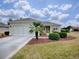 House exterior featuring a two-car garage, palm tree, and well-maintained landscaping at 14267 Se 85Th Ter, Summerfield, FL 34491