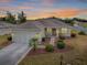 Single-story home with a screened garage and landscaped yard at sunset at 14267 Se 85Th Ter, Summerfield, FL 34491