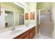 Main bathroom with double sinks, shower, and wood cabinets at 208 Desota Ct, The Villages, FL 32159