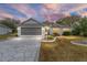 Single-story home with gray siding, a two-car garage, and a stone driveway at dusk at 2123 Barbosa Ct, The Villages, FL 32159