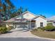 Tan house with screened-in garage, landscaping, and a paved driveway at 21509 Castle View Ct, Leesburg, FL 34748