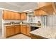 Well-lit kitchen featuring wood cabinets, granite countertops, a double sink, and modern black appliances at 21721 Loch Haven Pass, Leesburg, FL 34748