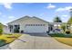 Beige house with a two-car garage and a covered patio at 2214 Quinn Ln, The Villages, FL 32162