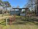 Red metal gate opens to barnyard with sheds and fenced pastures at 2403 County Road 416N, Lake Panasoffkee, FL 33538