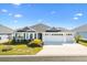 White two-car garage home with gray roof and landscaping at 2484 Lynette Ave, The Villages, FL 32163