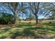 Landscaped backyard with large oak trees and golf course view at 25236 River Crest Dr, Leesburg, FL 34748