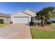 White house with two-car garage, palm trees, and a landscaped yard at 2565 Edenville Path, The Villages, FL 32162