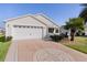 White house with two-car garage, palm trees, and landscaped yard at 2565 Edenville Path, The Villages, FL 32162