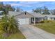 One-story home with gray siding, palm trees, and driveway at 26154 Newcombe Cir, Leesburg, FL 34748