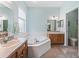 Bathroom with corner jacuzzi tub, double vanity, and light-colored tile at 353 Ranchwood Dr, Leesburg, FL 34748