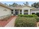 Front entry with brick walkway, lush landscaping, and decorative screen door at 353 Ranchwood Dr, Leesburg, FL 34748