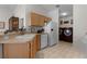 Galley kitchen features wood cabinets, white appliances, and a laundry closet at 424 Rose Croft Ter, The Villages, FL 32162