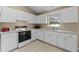 White kitchen with electric range, microwave, and double sink at 438 Woodview Dr, Tavares, FL 32778