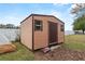 Tan storage shed in backyard with brown door and windows at 438 Woodview Dr, Tavares, FL 32778