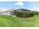 Landscaped backyard with a privacy hedge and a screened-in pool area at 4406 Creighton Loop, The Villages, FL 32163