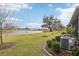 Backyard view of a pond, landscaping, and AC units at 5278 Dragonfly Dr, Wildwood, FL 34785