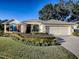 House exterior featuring a two-car garage and well-manicured landscaping at 581 Society Hill Cir, The Villages, FL 32162