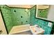 Green tiled bathroom, bathtub, and sink at 819 Edgewater Dr, Eustis, FL 32726