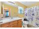 Bathroom with wood cabinets and butterfly-themed shower curtain at 860 Evelynton Loop, The Villages, FL 32162