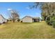 Backyard view of tan house, featuring a spacious lawn at 860 Evelynton Loop, The Villages, FL 32162