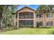 An impressive back exterior featuring a screened-in porch overlooking a well-maintained lawn and lush greenery at 102 Camino Real Blvd # 102, Howey In The Hills, FL 34737