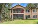 An impressive back exterior featuring a screened-in porch overlooking a well-maintained lawn and lush greenery at 102 Camino Real Blvd # 102, Howey In The Hills, FL 34737