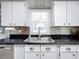 Bright kitchen features white cabinets, dark countertops, and a double sink at 1026 Capella Dr, Tavares, FL 32778