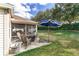 Back patio with ample seating, fire pit and shade umbrella overlooking lush lawn at 12037 Ne 51St Cir, Oxford, FL 34484