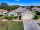 Single-story house with light green walls, a two-car garage, and well-maintained landscaping at 12327 Se 92Nd Court Rd, Summerfield, FL 34491