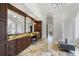 Spacious bathroom with beautiful wood cabinetry, marble flooring, and a view towards a large window at 15118 Pendio Dr, Bella Collina, FL 34756