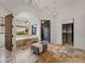Bright bathroom showcases a soaking tub under a window and a chandelier above a stone-tiled floor at 15118 Pendio Dr, Bella Collina, FL 34756