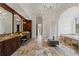Spacious bathroom with beautiful wood cabinetry, marble flooring, and a view towards a soaking tub at 15118 Pendio Dr, Bella Collina, FL 34756