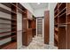 Walk-in closet boasts custom wood shelving, drawers, and cabinets with stone tile flooring at 15118 Pendio Dr, Bella Collina, FL 34756