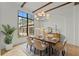 Bright dining room with exposed wood beams, a modern chandelier, and a large window at 15118 Pendio Dr, Bella Collina, FL 34756