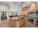 Open-concept kitchen with custom cabinets, granite countertops, stainless appliances, and stone floors at 15118 Pendio Dr, Bella Collina, FL 34756