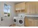 Well-equipped laundry area with washer, dryer, and overhead cabinets and adjacent to the exterior door at 15118 Pendio Dr, Bella Collina, FL 34756