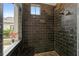 Stylish bathroom featuring a black tiled shower with dual shower heads and a window at 15118 Pendio Dr, Bella Collina, FL 34756