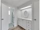 White bathroom vanity with oval mirror and shower at 16 Captains Pt, Fruitland Park, FL 34731
