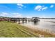 A picturesque lakeside dock with multiple boat slips and covered gazebo areas under a blue sky with clouds at 16428 Good Hearth Blvd, Clermont, FL 34711