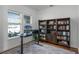 A bright home office features built-in dark wood bookshelves on a plush grey rug with natural light at 16428 Good Hearth Blvd, Clermont, FL 34711