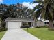Tan house with a blue door, palm trees, and a well-manicured lawn at 25141 Clifford Hl, Leesburg, FL 34748