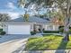 House exterior with a white garage door, landscaping, and a large tree at 26748 White Plains Way, Leesburg, FL 34748