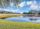 Serene pond view, lush landscaping, and golf course in background at 26748 White Plains Way, Leesburg, FL 34748