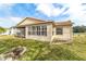 Back exterior view of a tan house with a screened porch and well-maintained lawn at 3200 Woodridge Dr, The Villages, FL 32162